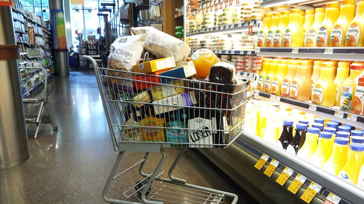 A filled shopping cart in a grocery aisle.