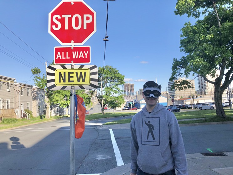 Steve MacKay poses with one of the new all-way stop signs at the intersection of Robie Street and Stairs Street.