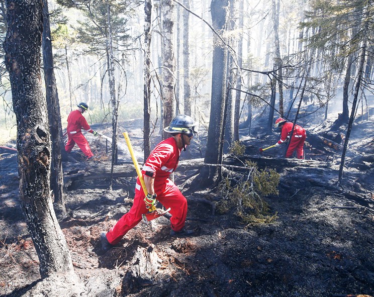 Three firefighters work to put out a wildfire in the Tantallon area on May 30, 2023.