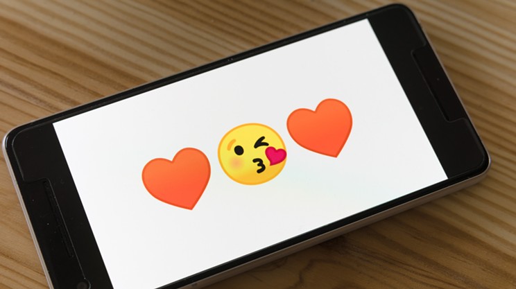 An iPad screen displaying two heart emojis and a kissing face emoji.